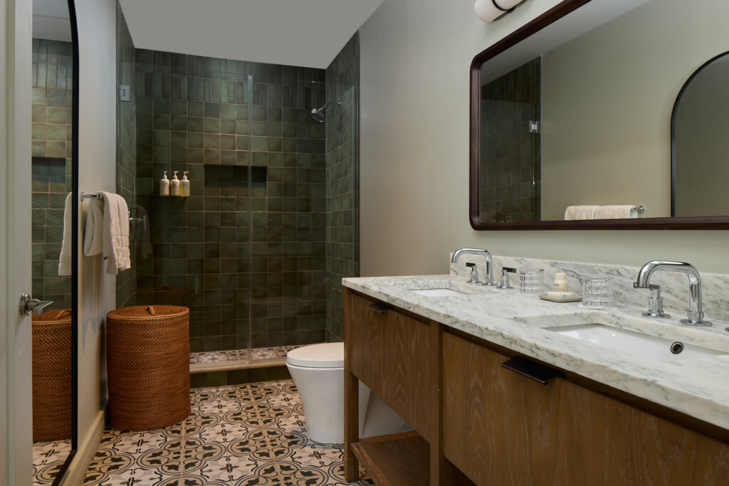 Hotel bathroom with patterned encaustic tile floor and marble vanity in Charleston