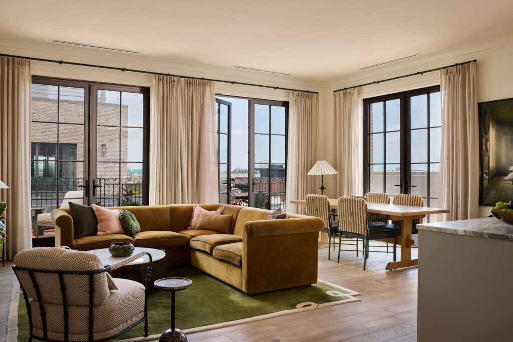 Sunlit suite living room with arched windows and velvet sofas at The Nickel Hotel, Charleston