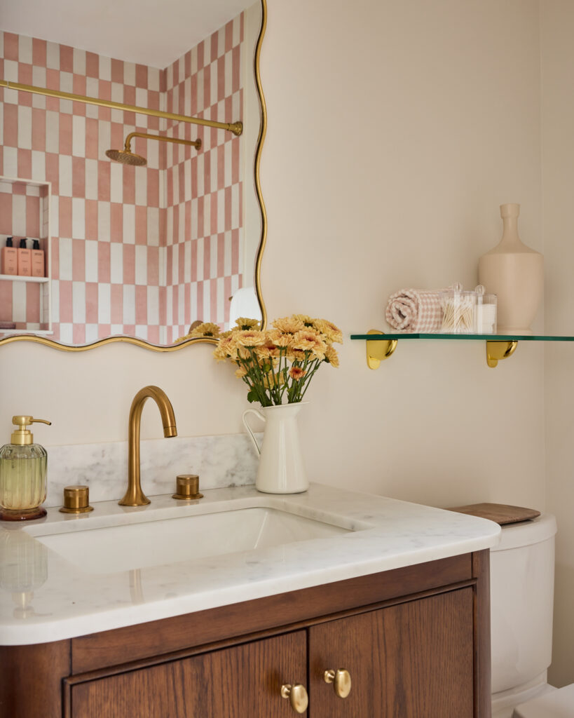 Bathroom vanity with scalloped mirror, brass faucet and yellow flowers at Spring Sanctuary