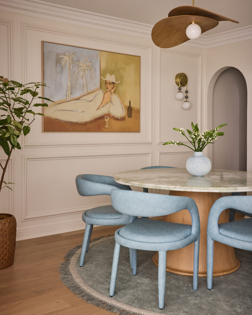 Round dining table with blue chairs, arched niche and artwork at Spring Sanctuary