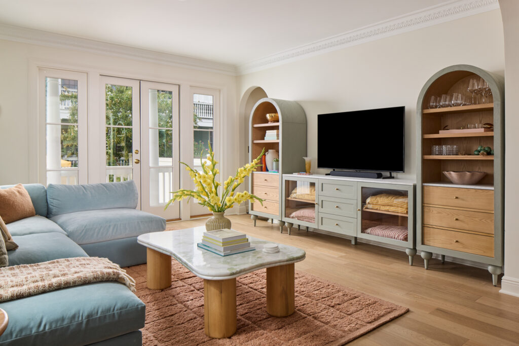 Living room with blue sectional, arched built-ins and French doors in a downtown Charleston Airbnb