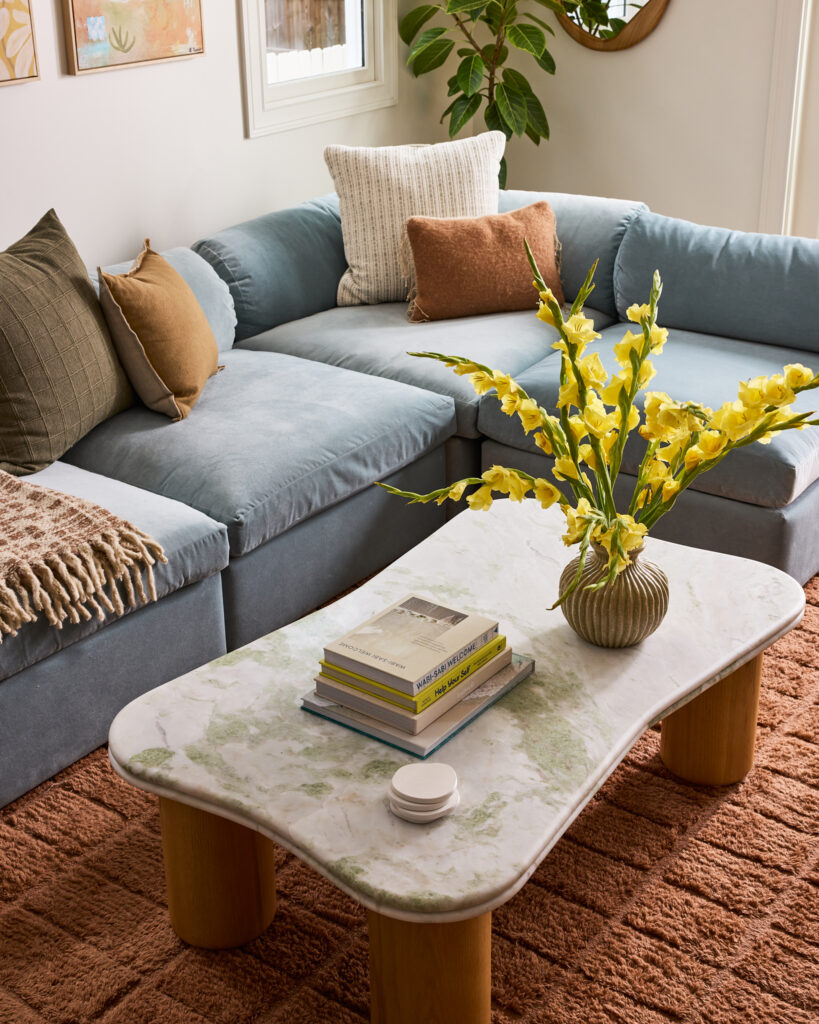 Blue sectional, marble coffee table and yellow florals in the Spring Sanctuary living room