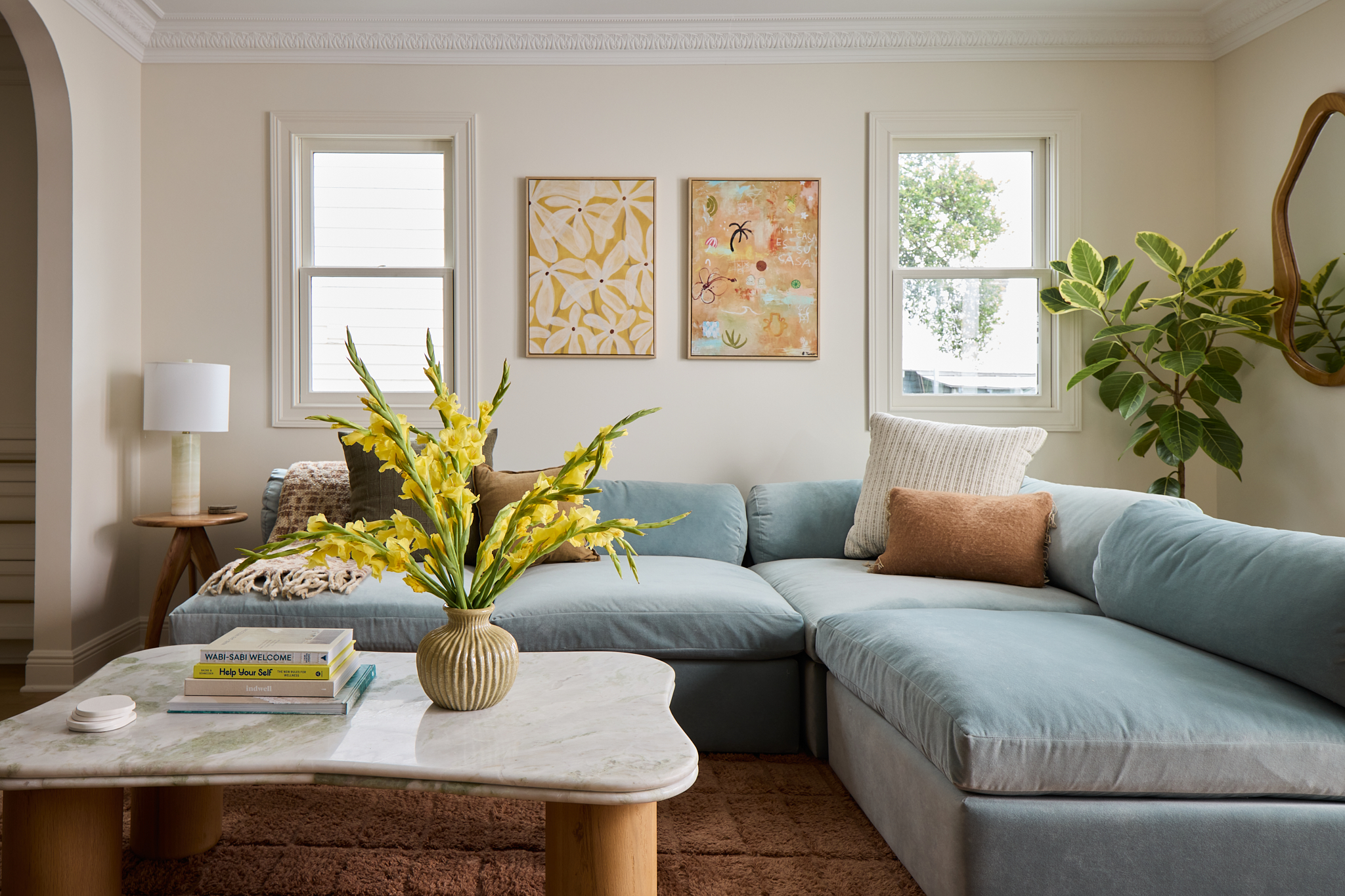 Blue sectional with yellow florals and framed art in a Charleston vacation rental living room